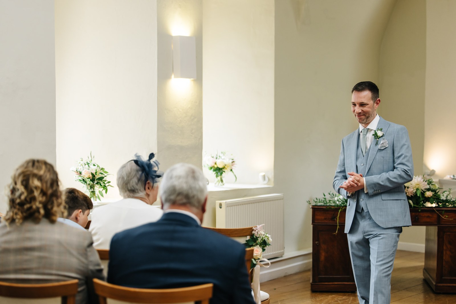 The groom waiting at the front of the ceremony room as guests take their seats