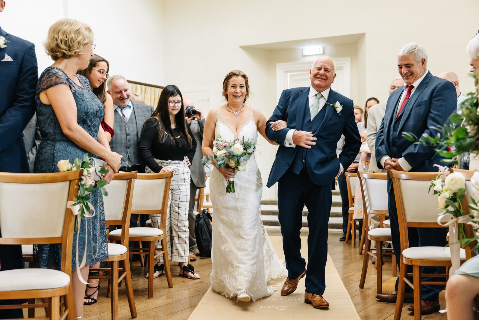 The bride walking down the aisle on her father's arm, guests standing