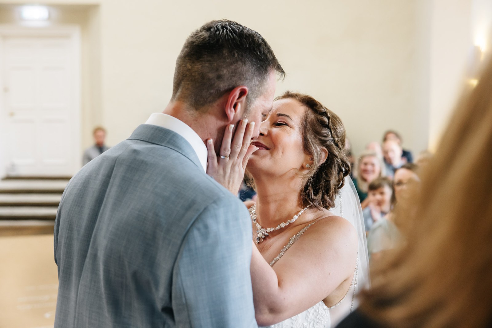 The couple's first kiss, the bride's hand resting on the groom's cheek