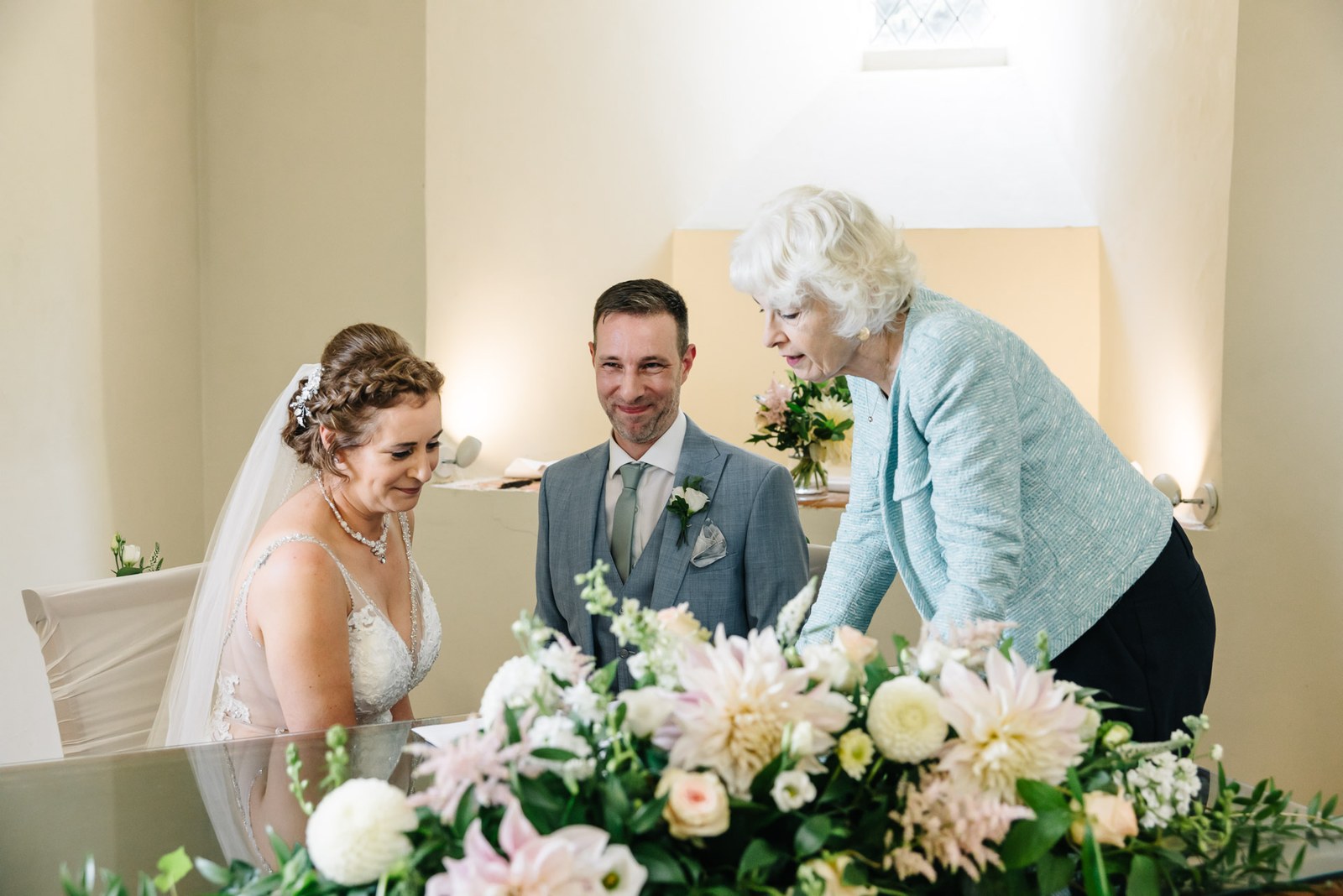 The registrar arranging flowers as the couple stand at the signing table