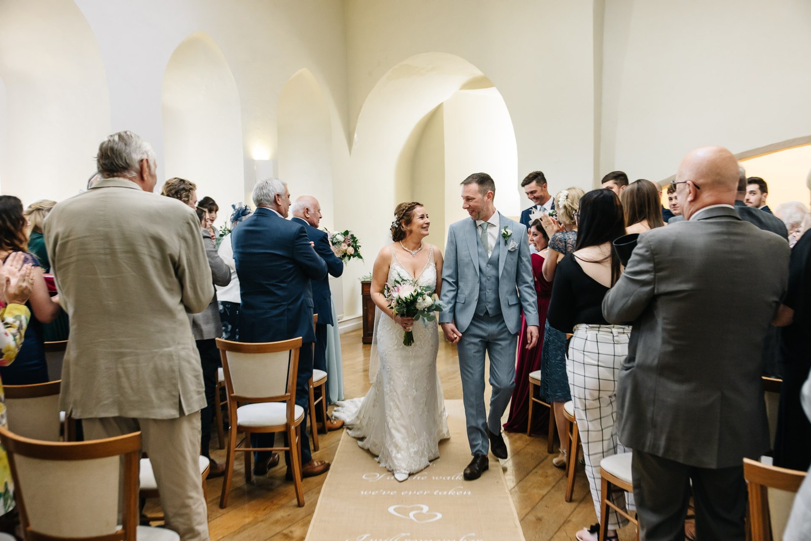 Newlyweds walking back down the aisle through the arched, panelled room