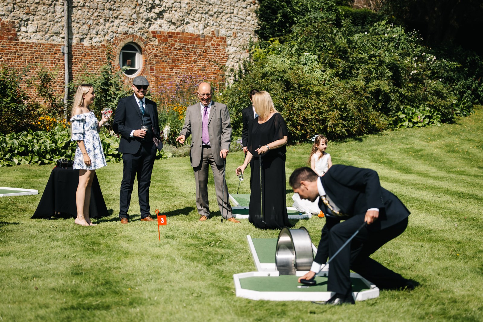 Guests trying lawn games on the grass below the brick walls of Farnham Castle