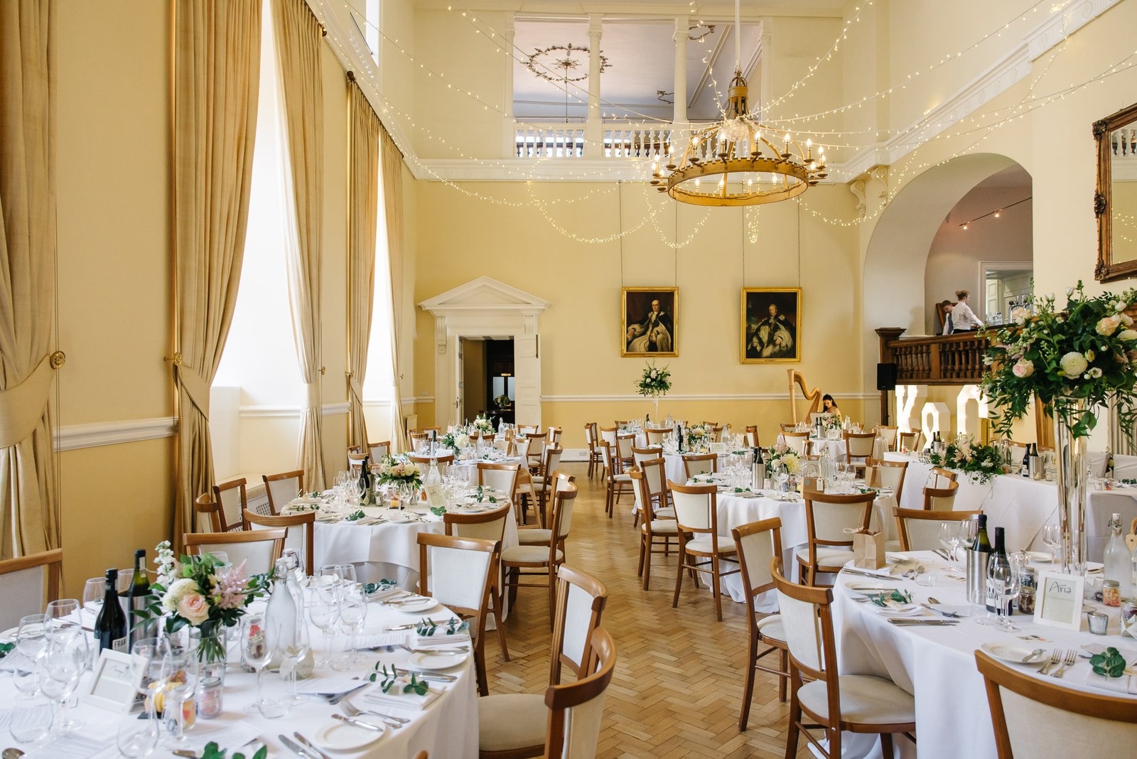 The dining room at Farnham Castle set with round tables beneath a chandelier and fairy lights