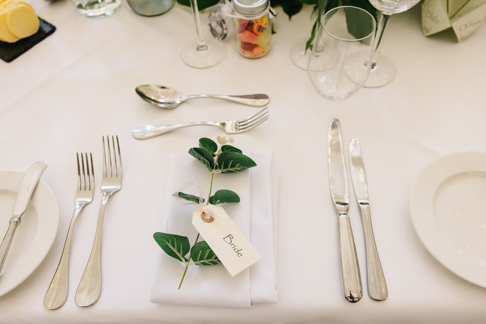 Close-up of a place setting with a leaf-tagged name card on a folded napkin
