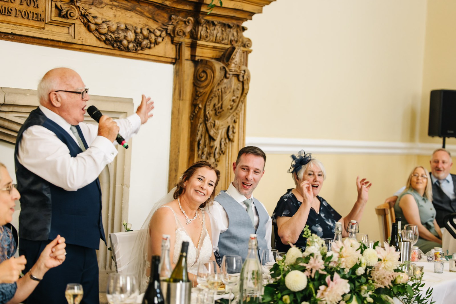 A guest giving a speech at the top table before the carved oak overmantel at Farnham Castle
