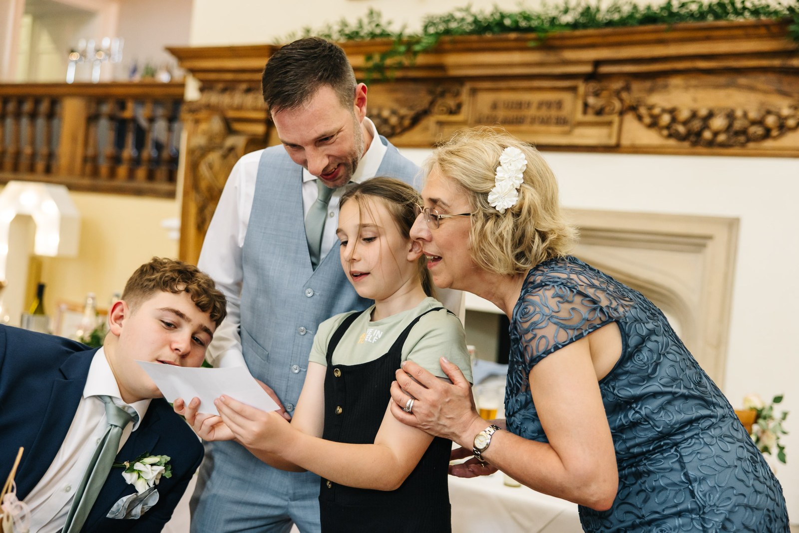 The groom watching as a young girl and family read a note during the reception