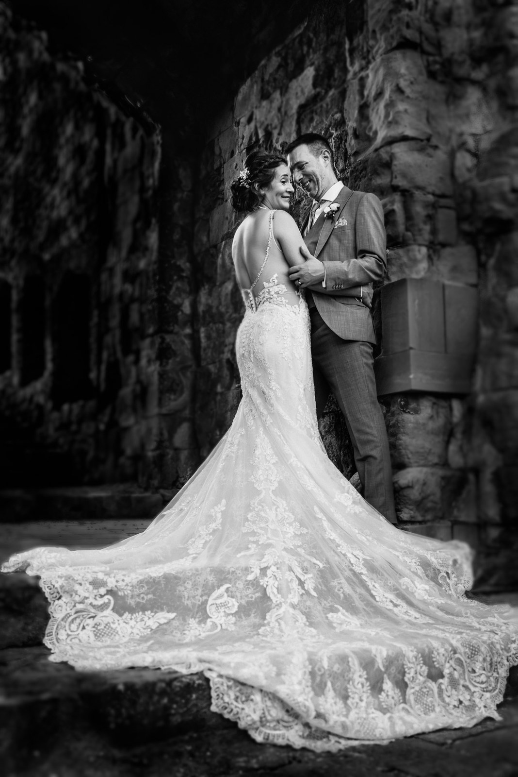 Black-and-white of the bride's lace train fanned across the Farnham Castle ruins floor