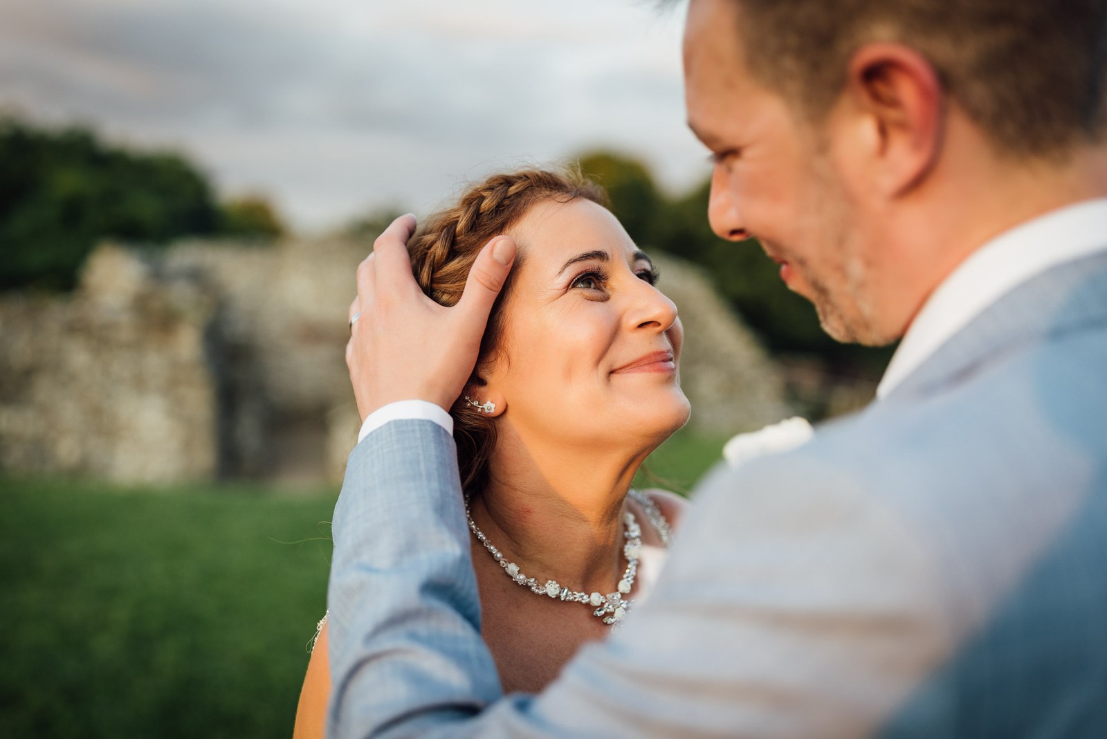Close-up of the groom cradling the bride's face, both bathed in evening light