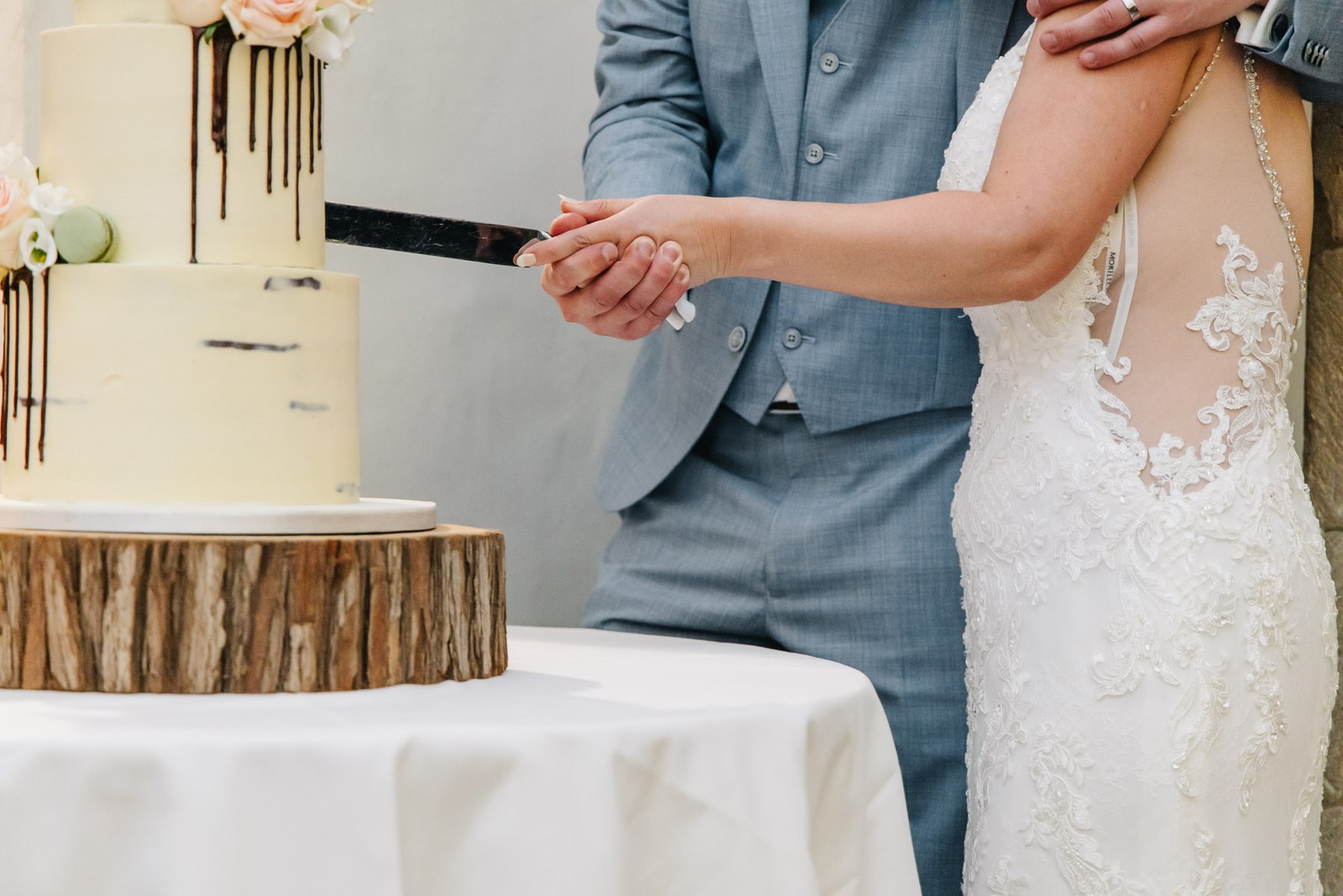 Close-up of the couple's hands cutting into the tiered wedding cake