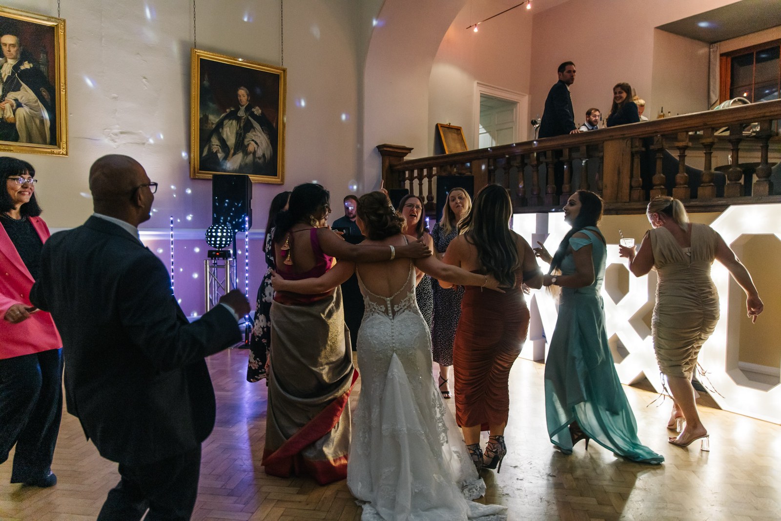 Guests dancing beneath oil portraits by the carved staircase at Farnham Castle