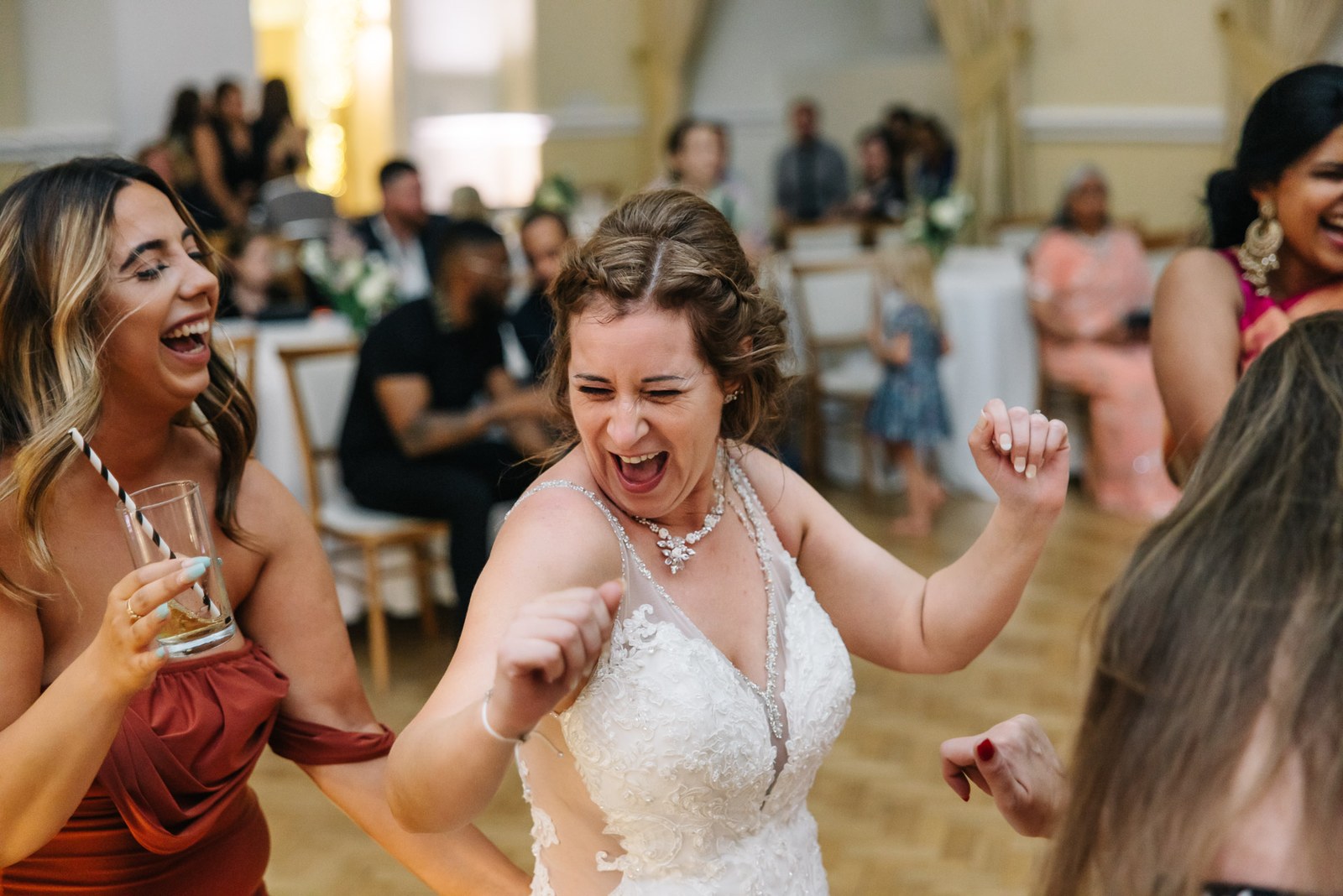 The bride dancing joyfully with a guest as others look on