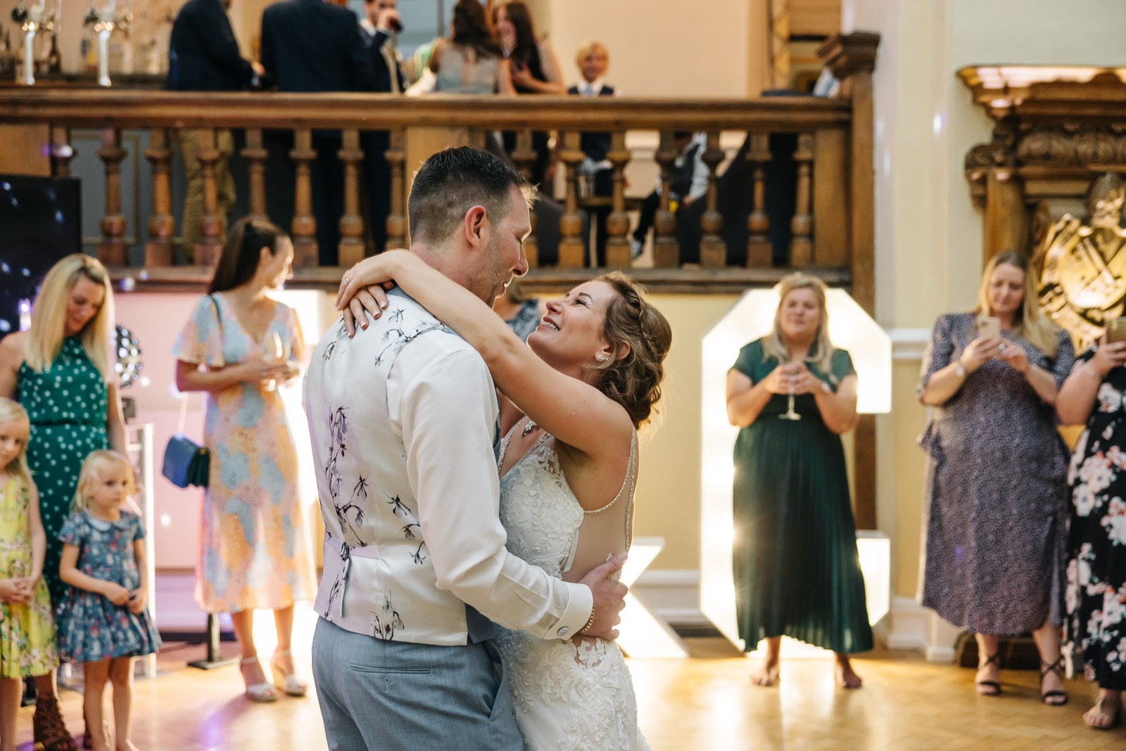 The couple's first dance, the bride's arms around the groom as guests watch