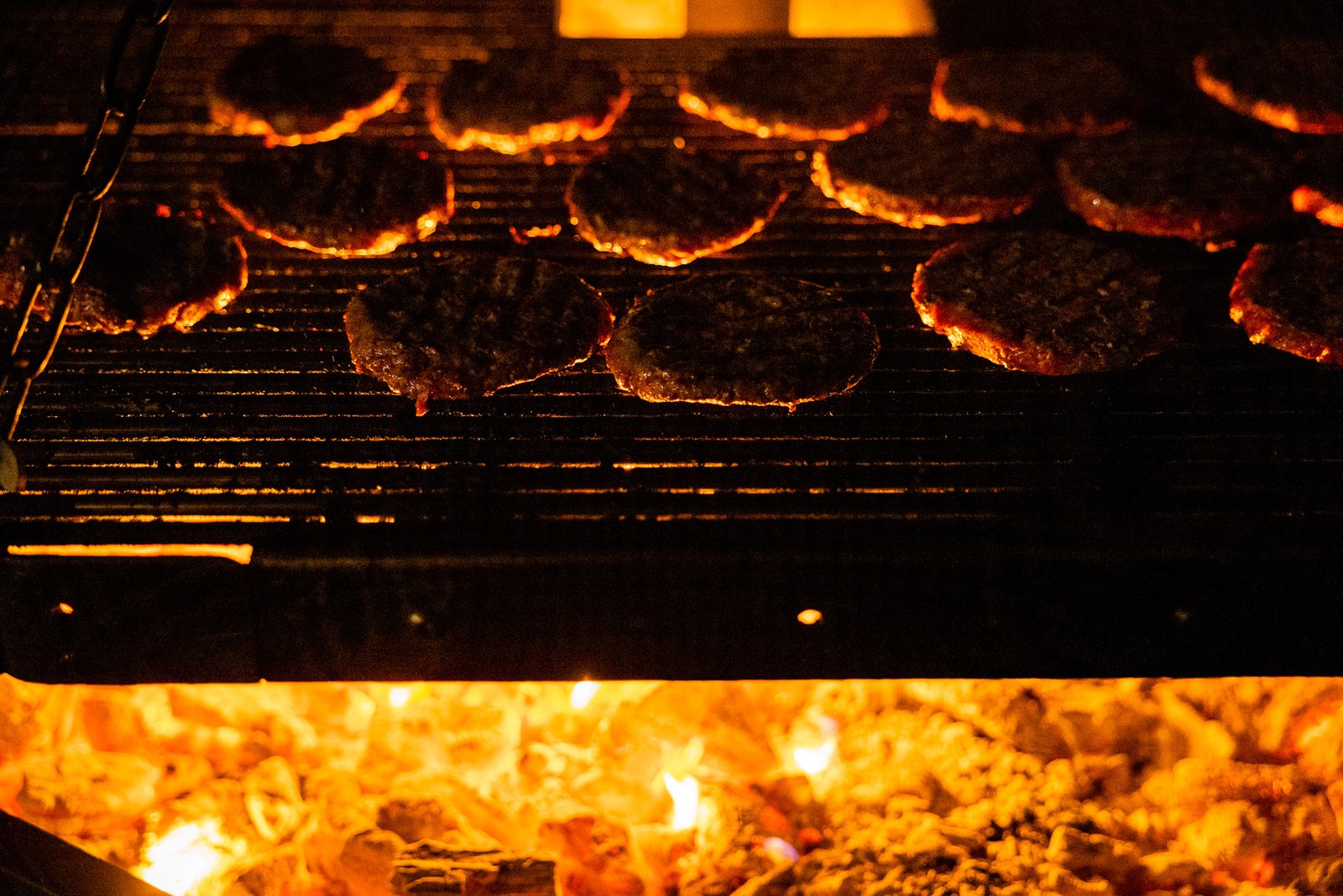 Burgers grilling over glowing coals at the evening barbecue