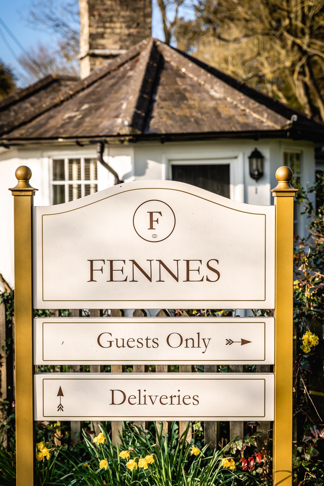 The Fennes venue sign framed by daffodils, welcoming guests up the drive