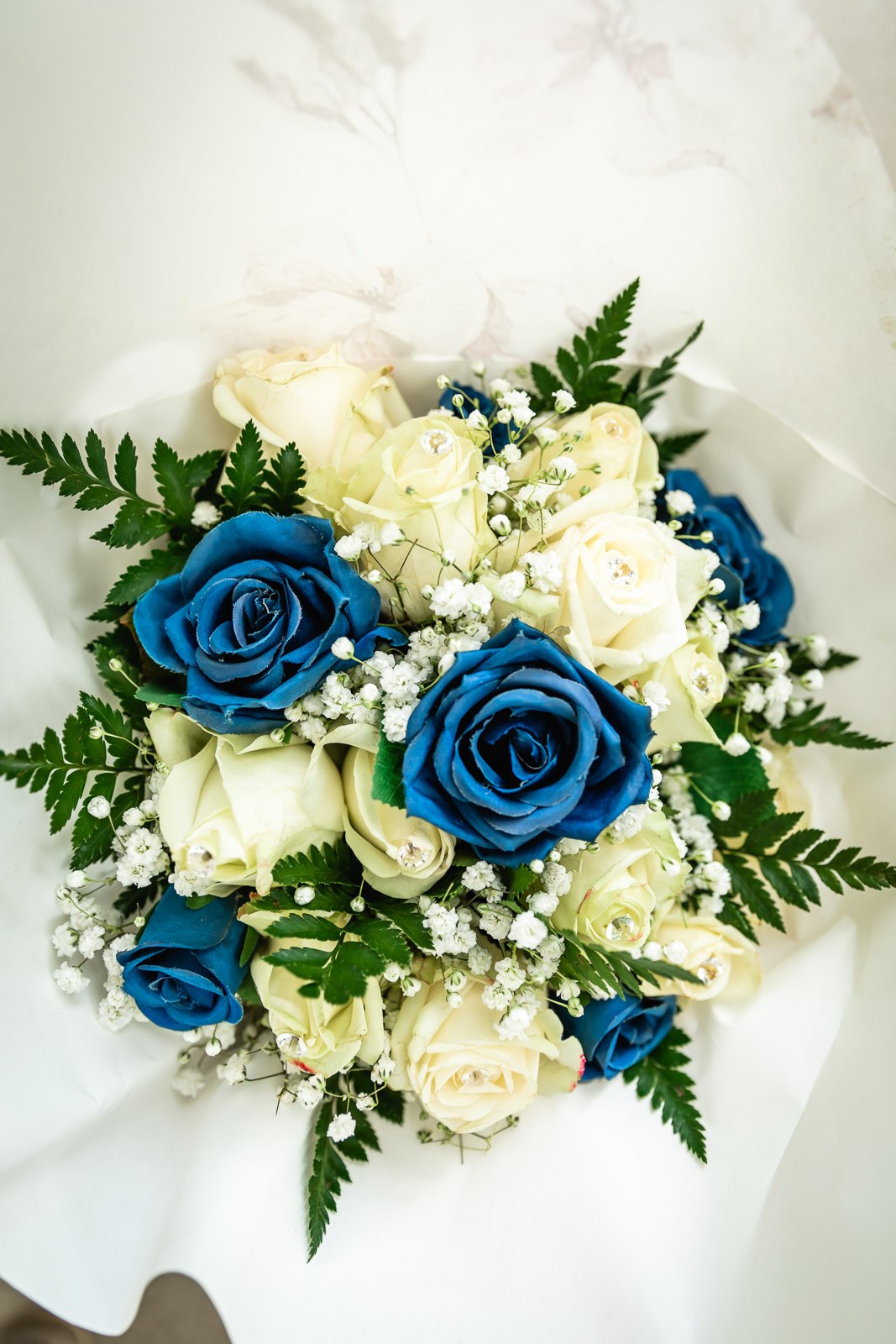 Close-up of the bridal bouquet of white and blue roses with gypsophila and fern