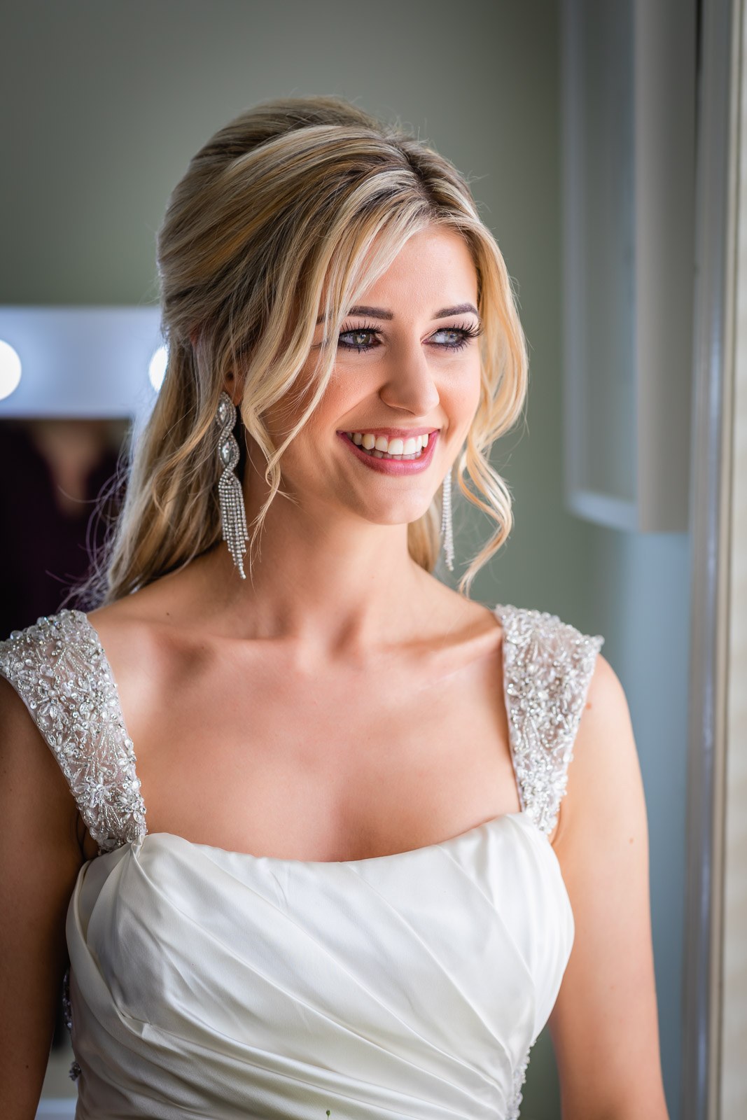 Bridal portrait, the bride smiling in her beaded gown and drop earrings