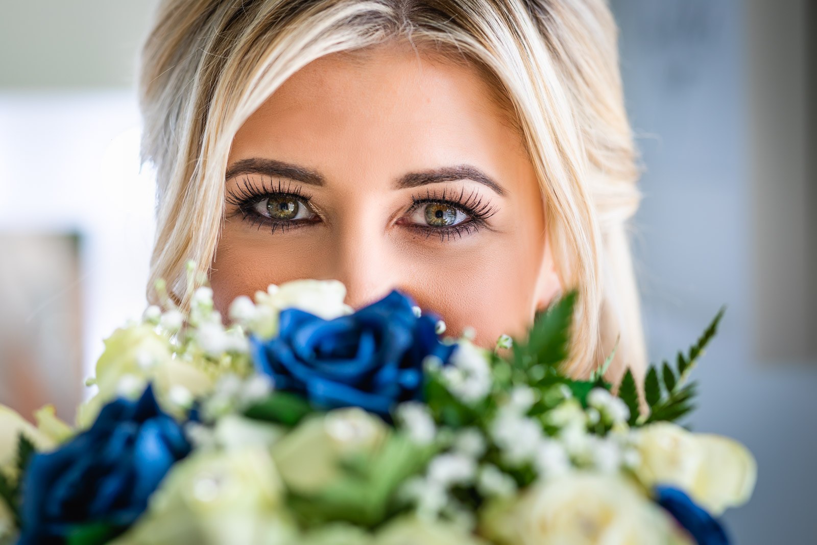The bride's eyes above her blue-and-white rose bouquet