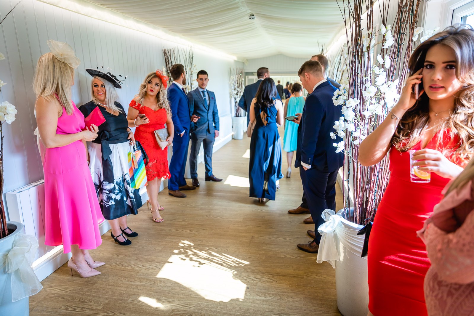 Guests mingling before the ceremony in a light room dressed with blossom branches