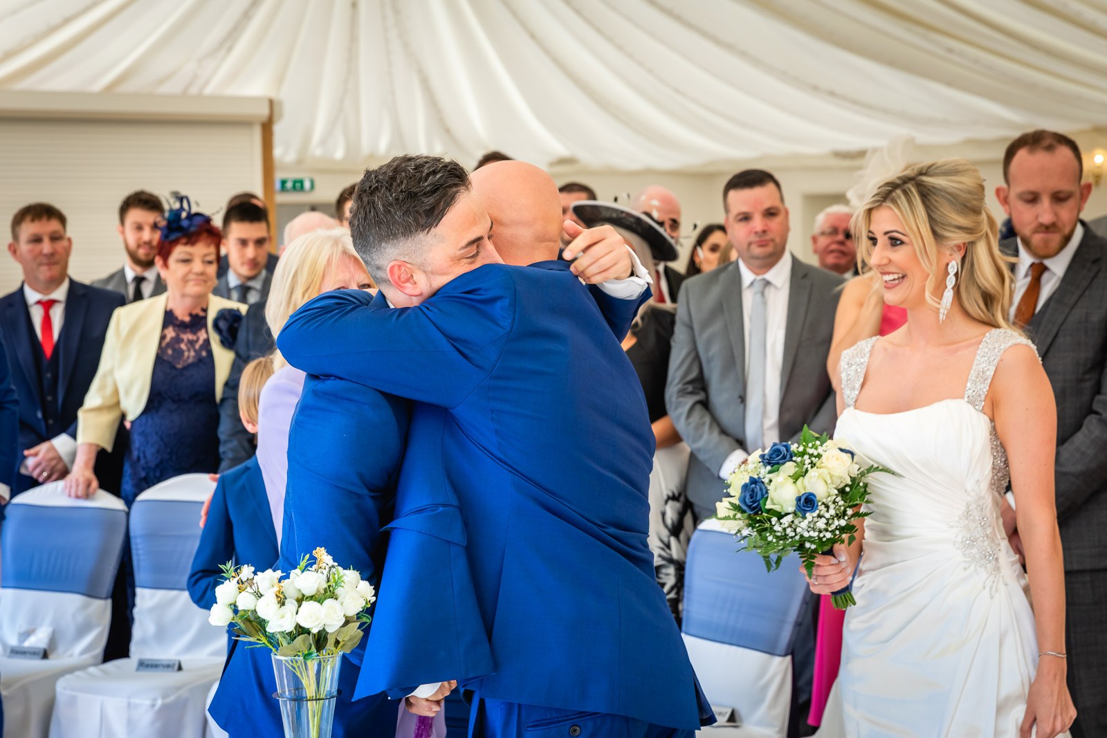The father of the bride hugging the groom at the front of the ceremony