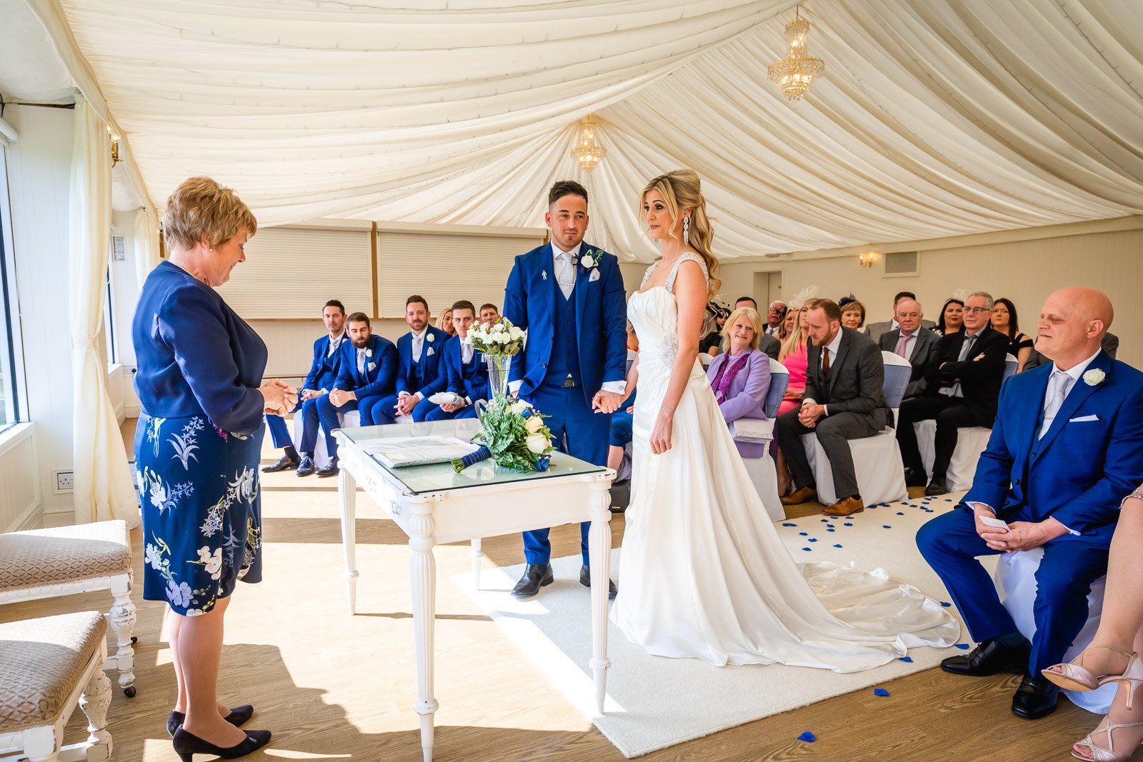 The couple before the registrar's table in the draped ceremony room at Fennes, guests seated