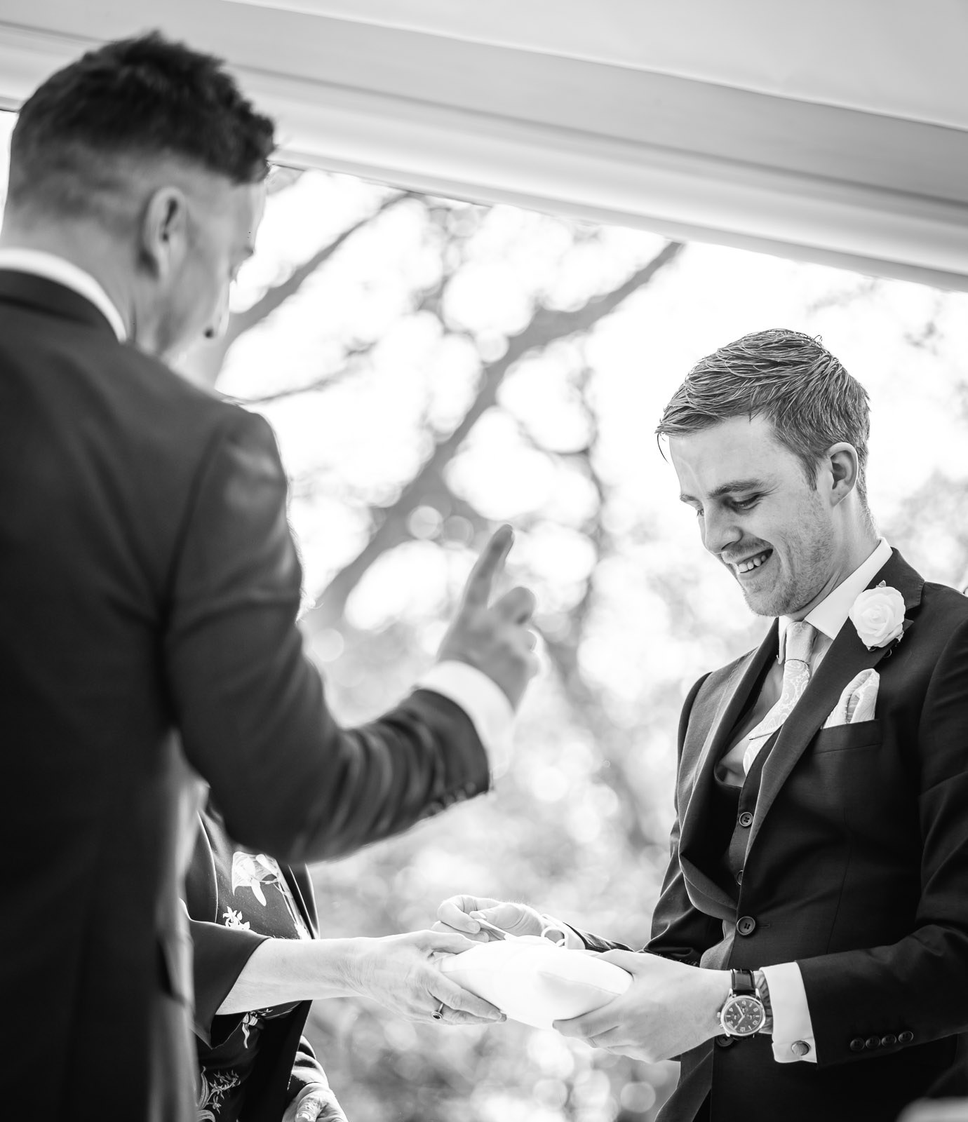 Black-and-white of the ring cushion being passed to the groom during the ceremony