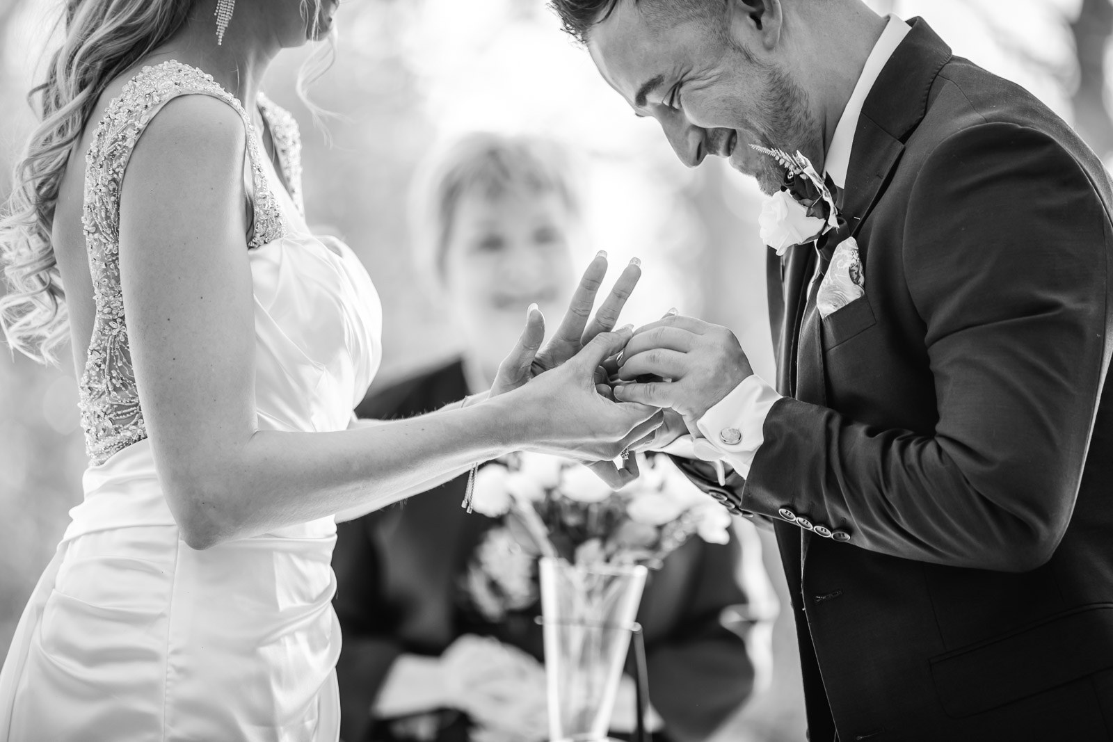 Black-and-white of the groom placing the ring on the bride's finger