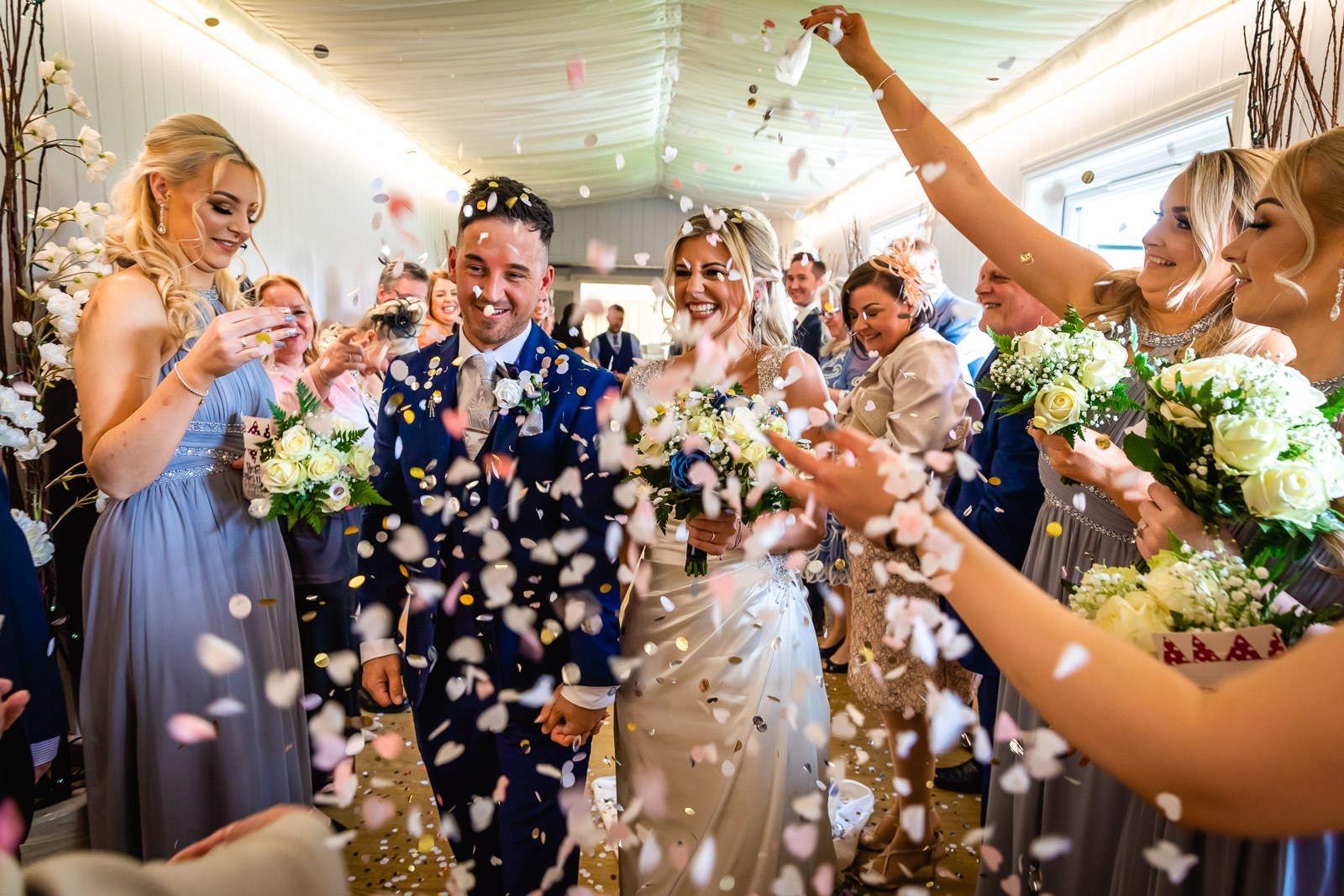 Newlyweds walking through a confetti shower thrown by their bridesmaids