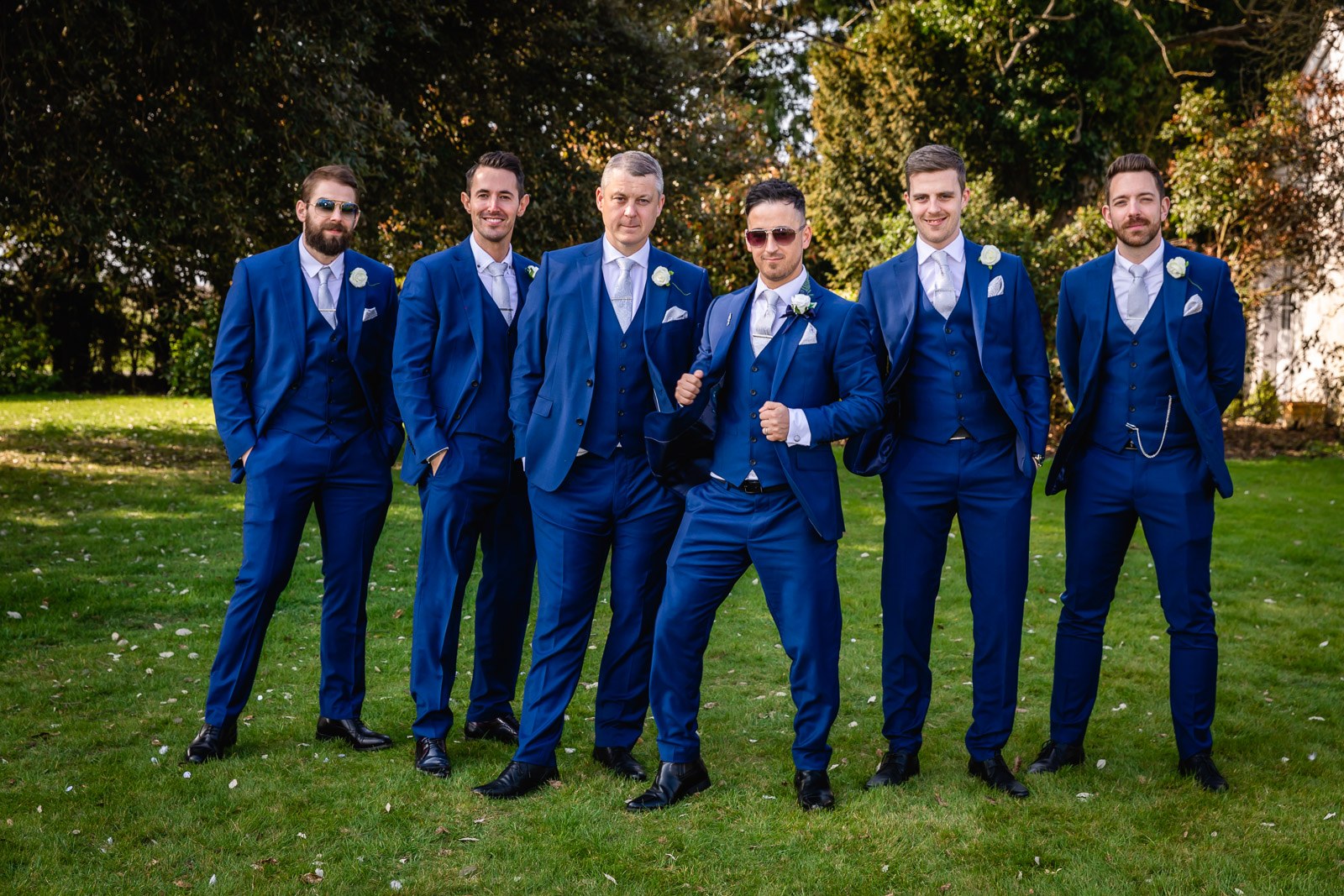 The groom with his groomsmen in blue suits on the lawn