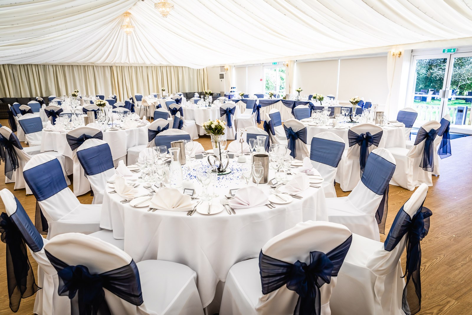 The reception room at Fennes laid with round tables in white and navy sashes