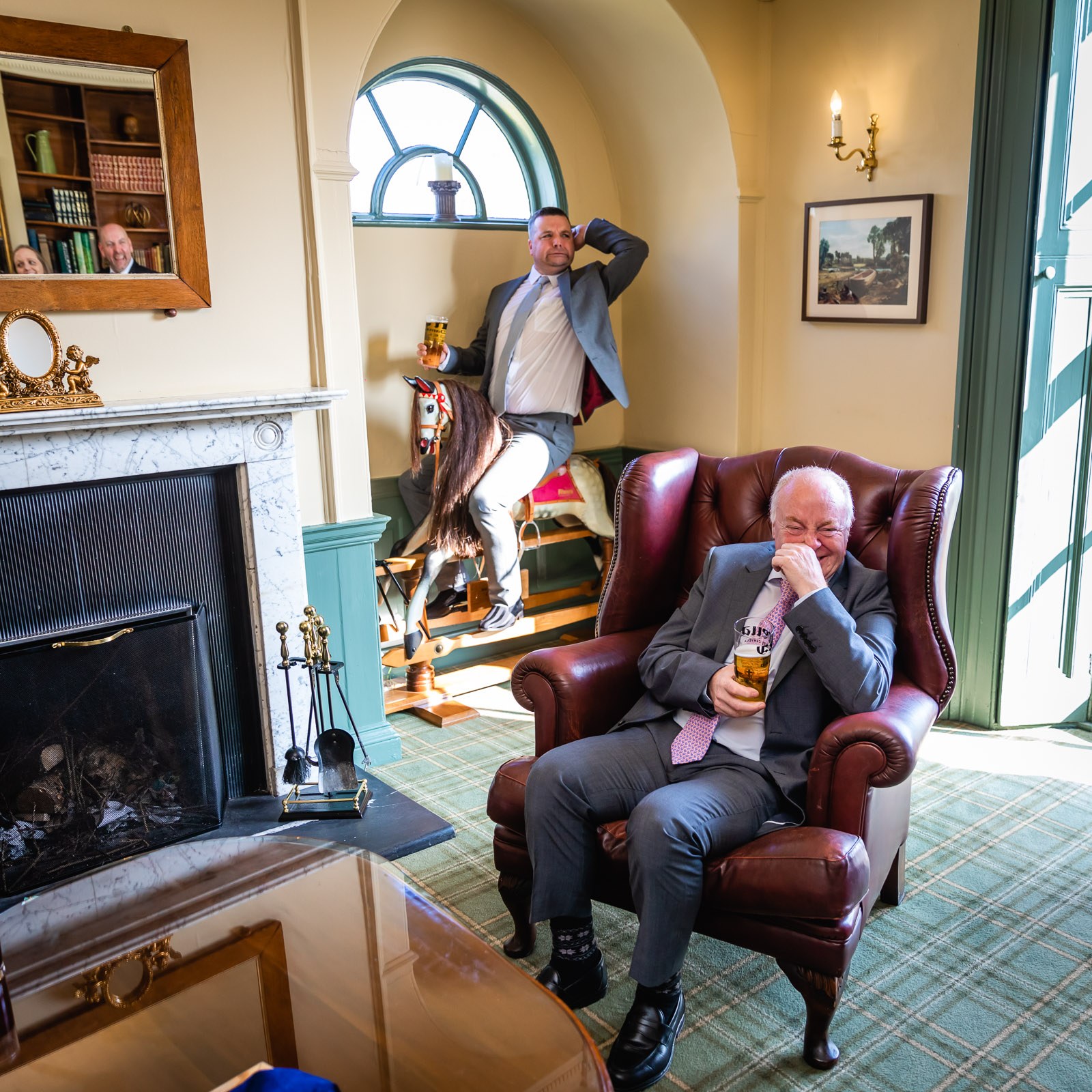 A guest laughing in a leather armchair by the marble fireplace at Fennes
