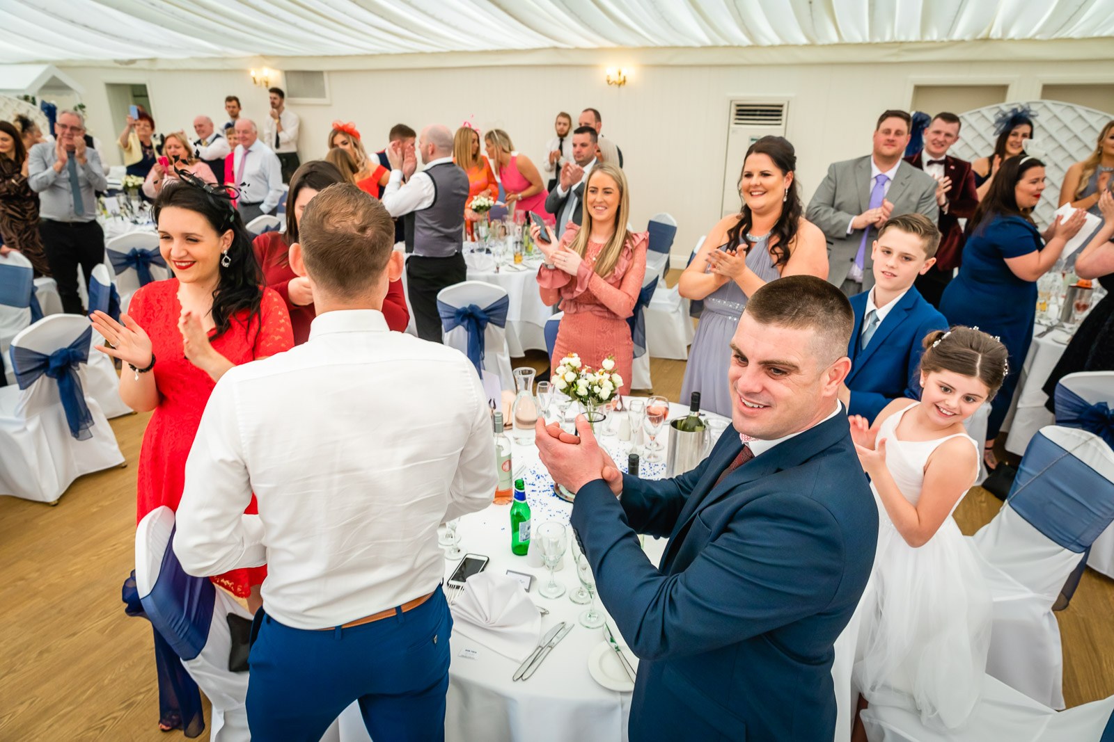Guests standing and applauding as the newlyweds arrive at the reception