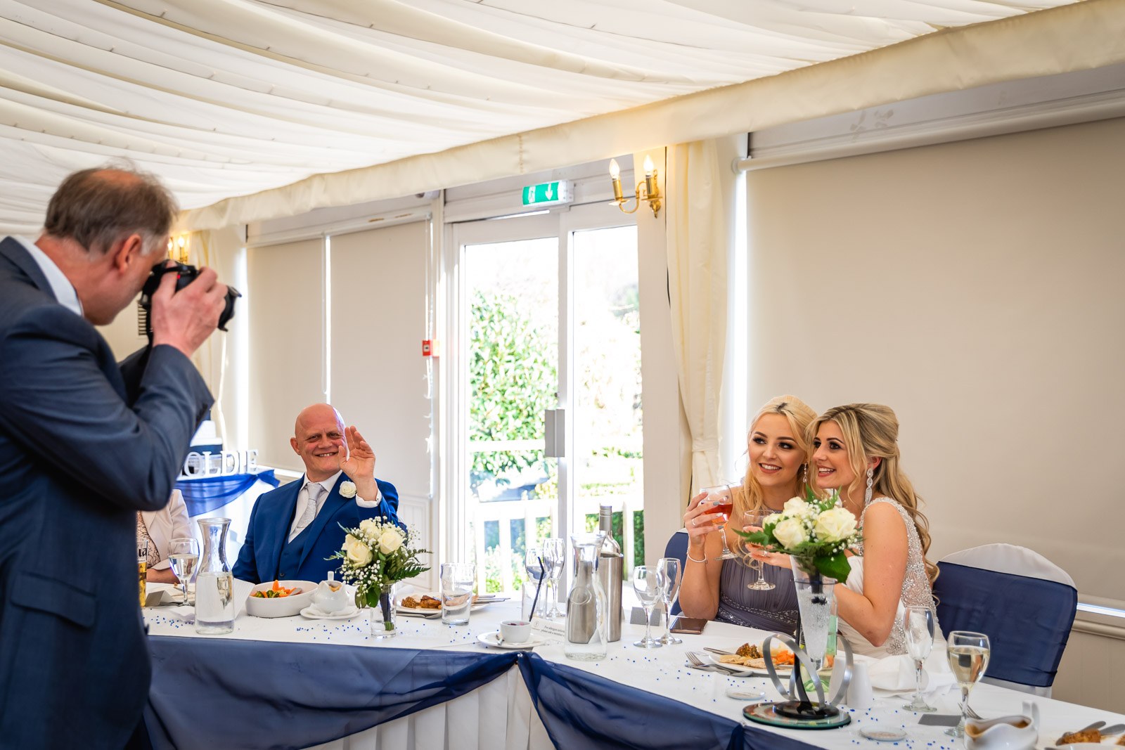 A guest photographing the top table dressed with navy sashes