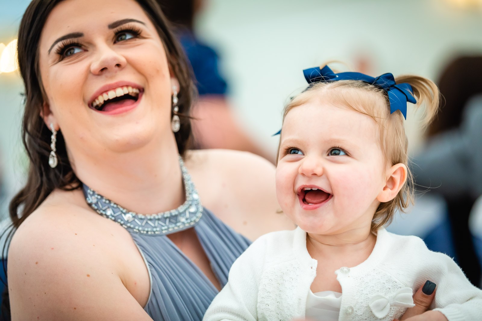 Close-up of a bridesmaid laughing with a toddler on her lap