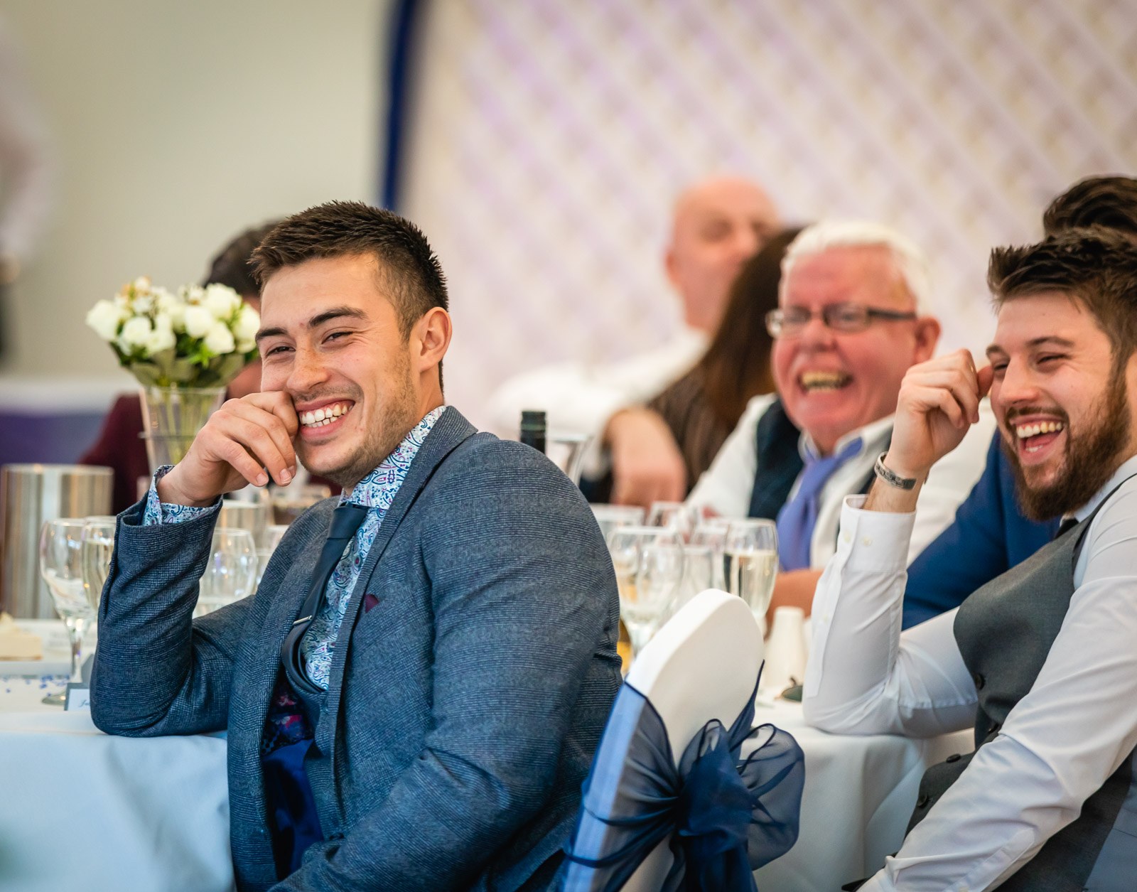 Guests at their table laughing during a speech
