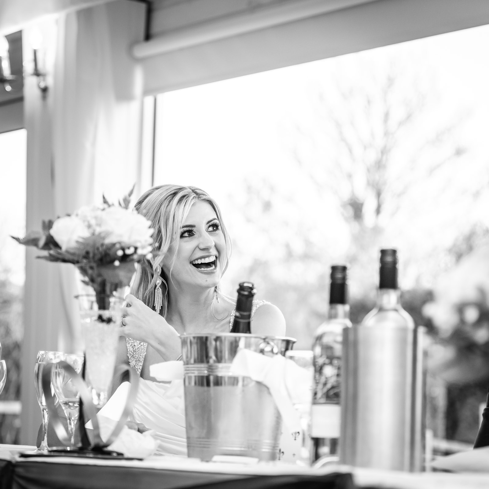 Black-and-white of the bride laughing during the speeches