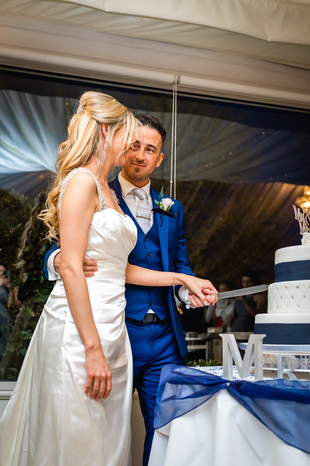 Bride and groom cutting the wedding cake together, 'Mr and Mrs' letters on the table