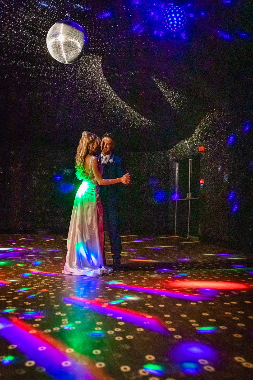 The couple's first dance beneath a disco ball on the lit dance floor
