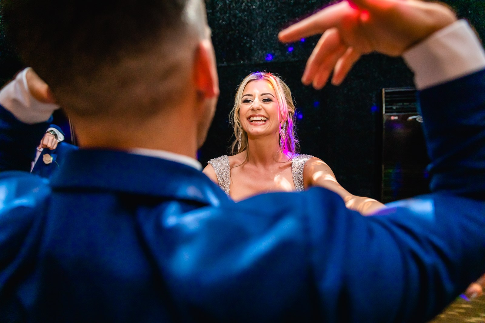The couple dancing together, the bride laughing amid coloured lights