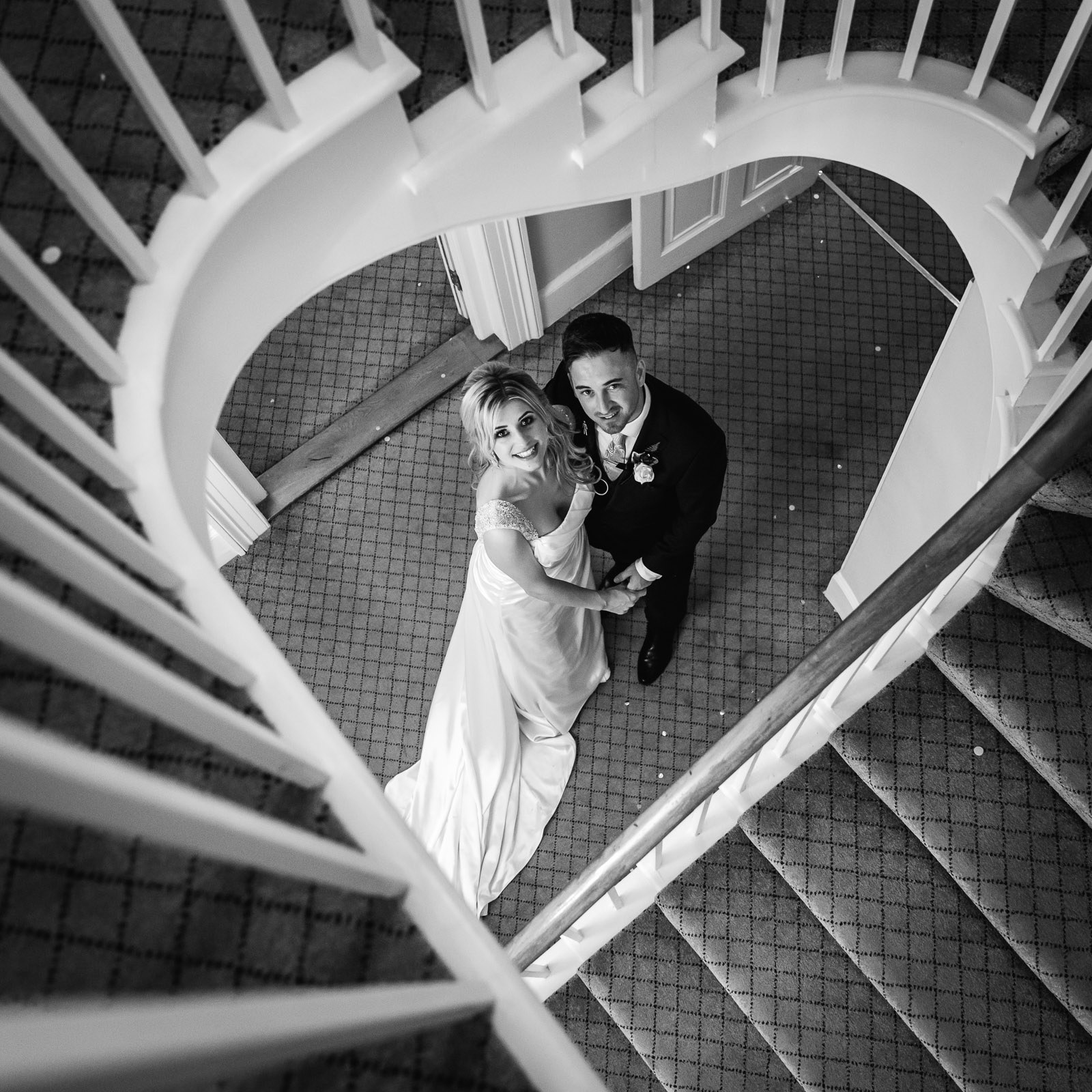 Overhead black-and-white of the couple at the foot of the spiral staircase at Fennes