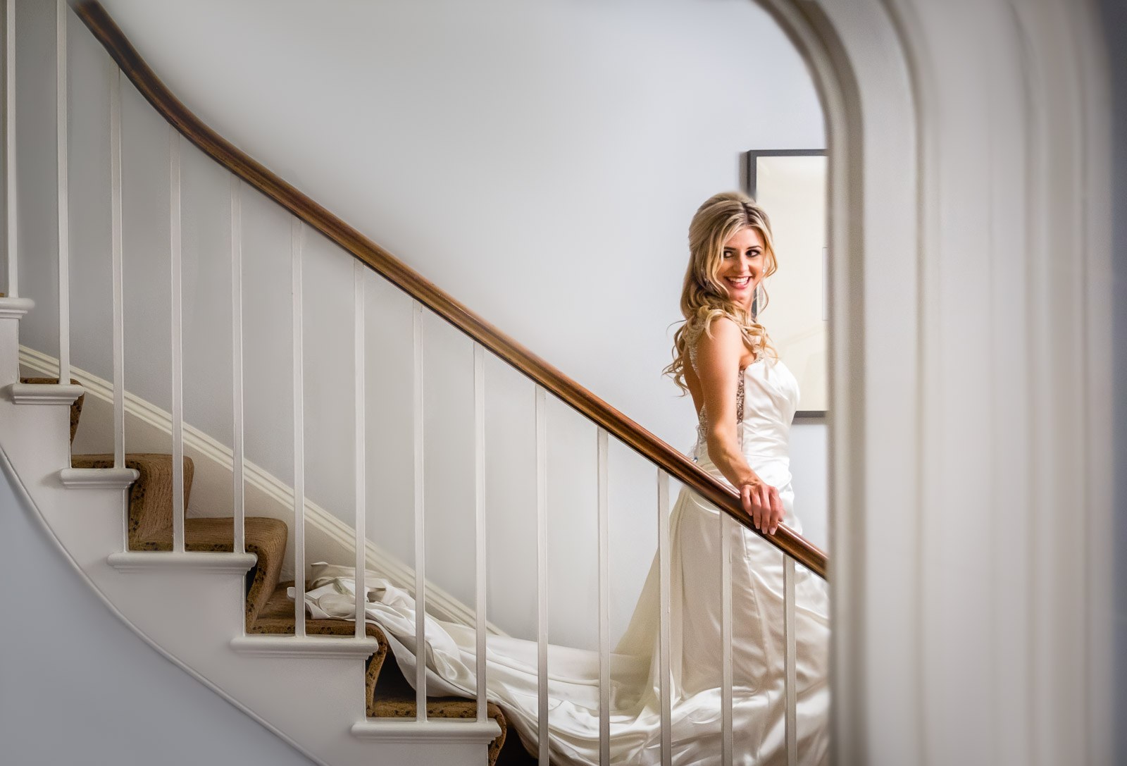 The bride on the staircase at Fennes, smiling back over her shoulder