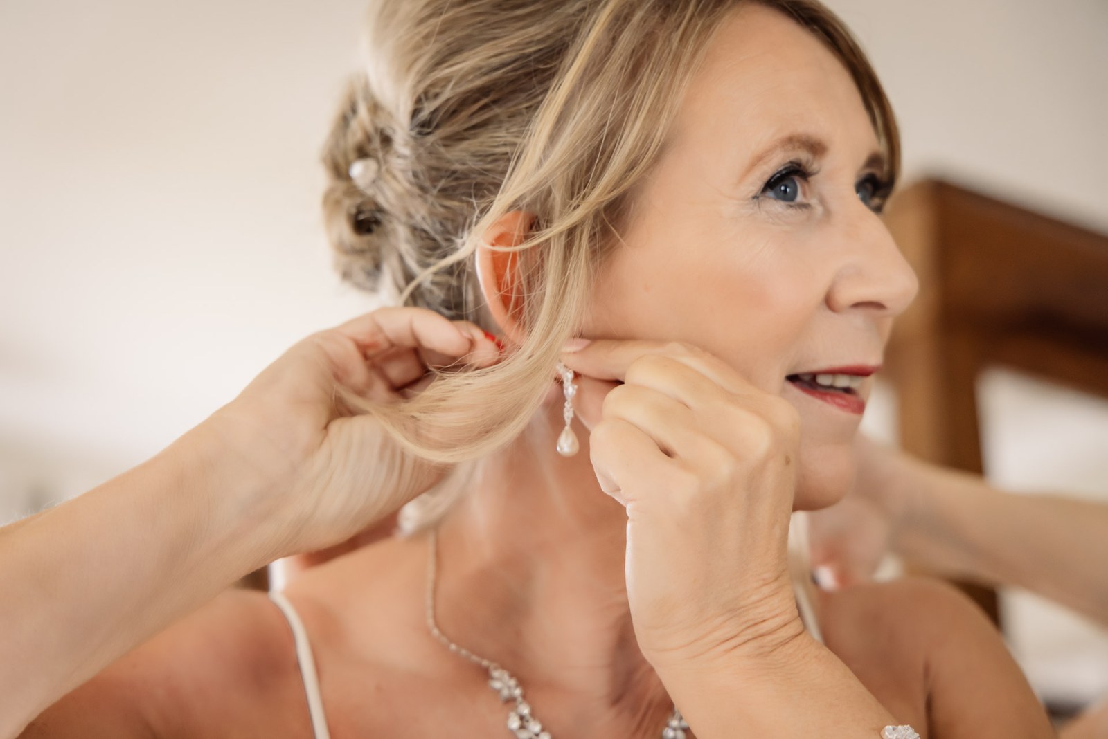 A drop earring being fastened for the bride as she finishes getting ready
