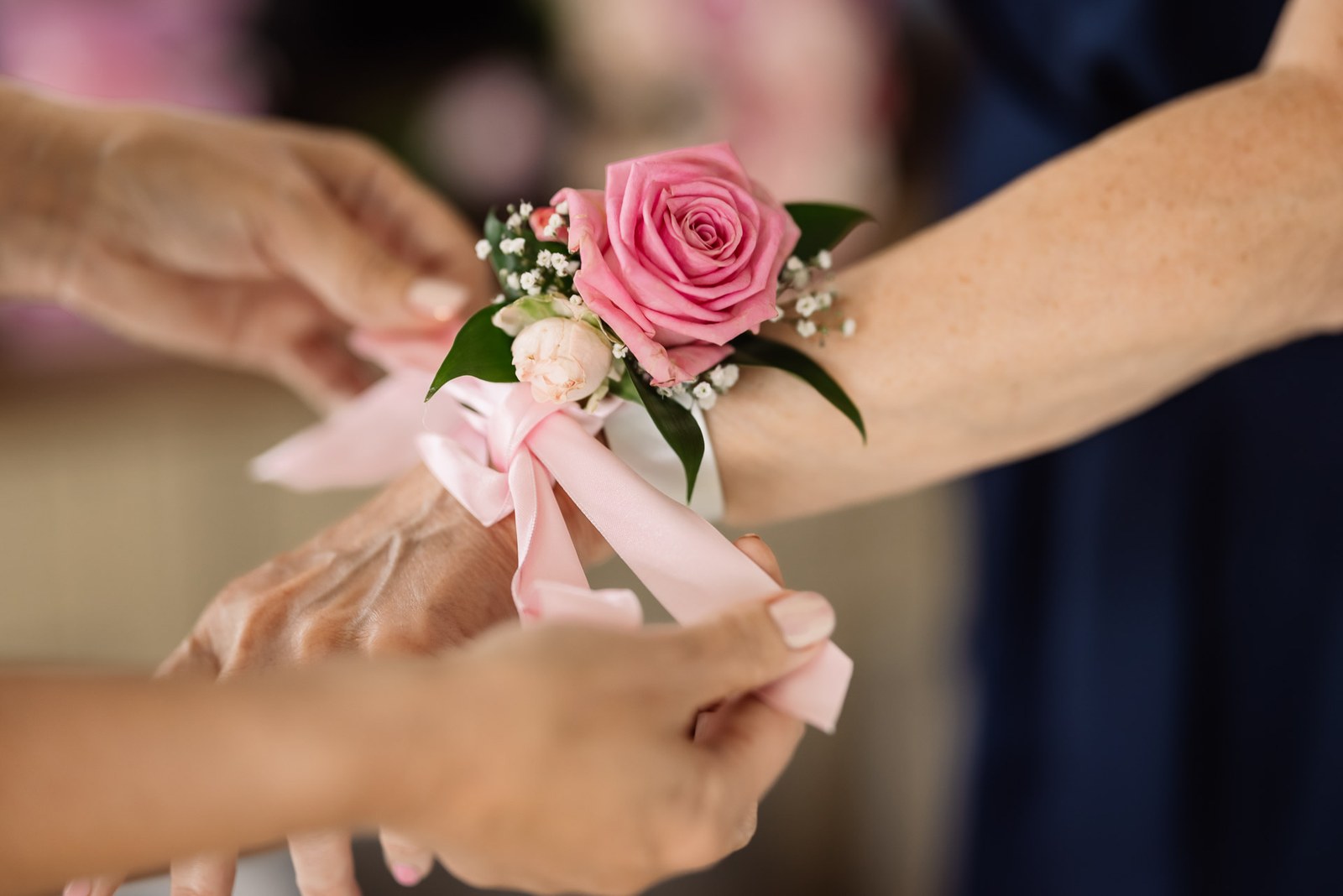 Close-up of a pink rose wrist corsage with a satin ribbon