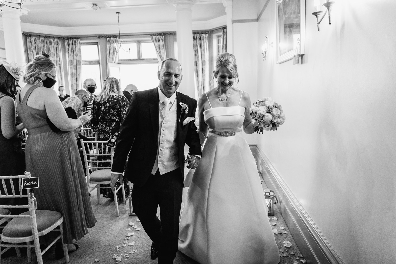 Black-and-white photograph of the newlyweds walking back up the aisle