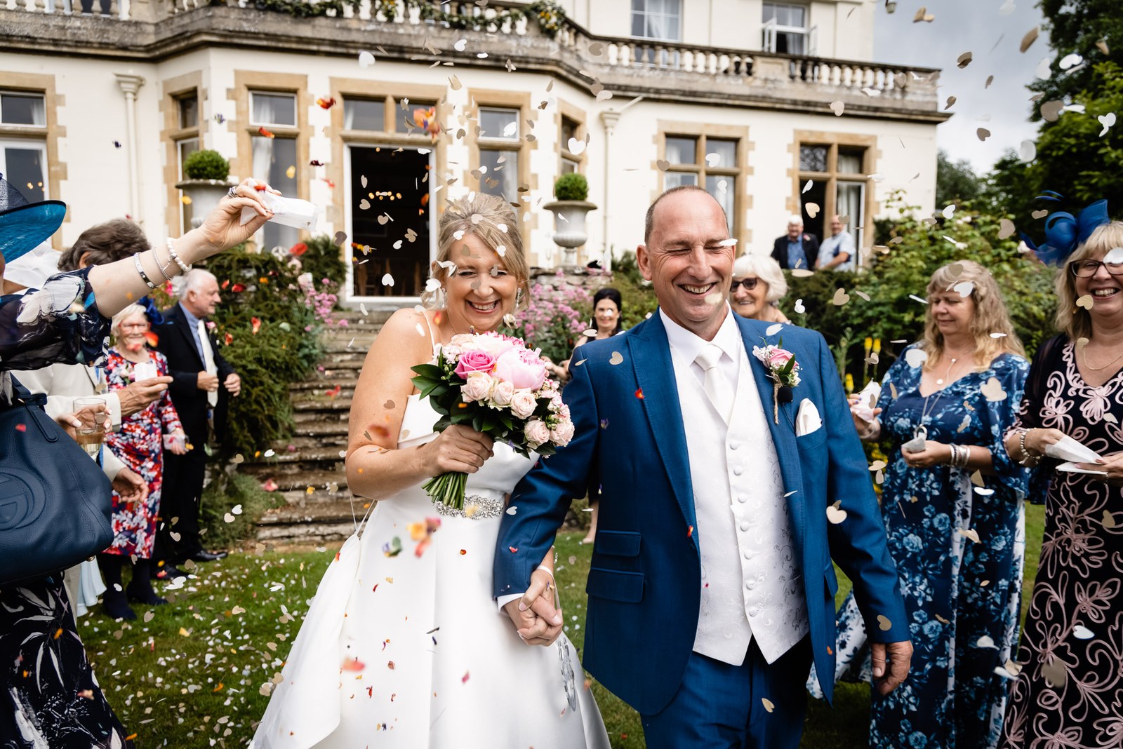 Confetti thrown over the bride and groom on the lawn outside Glenfall House