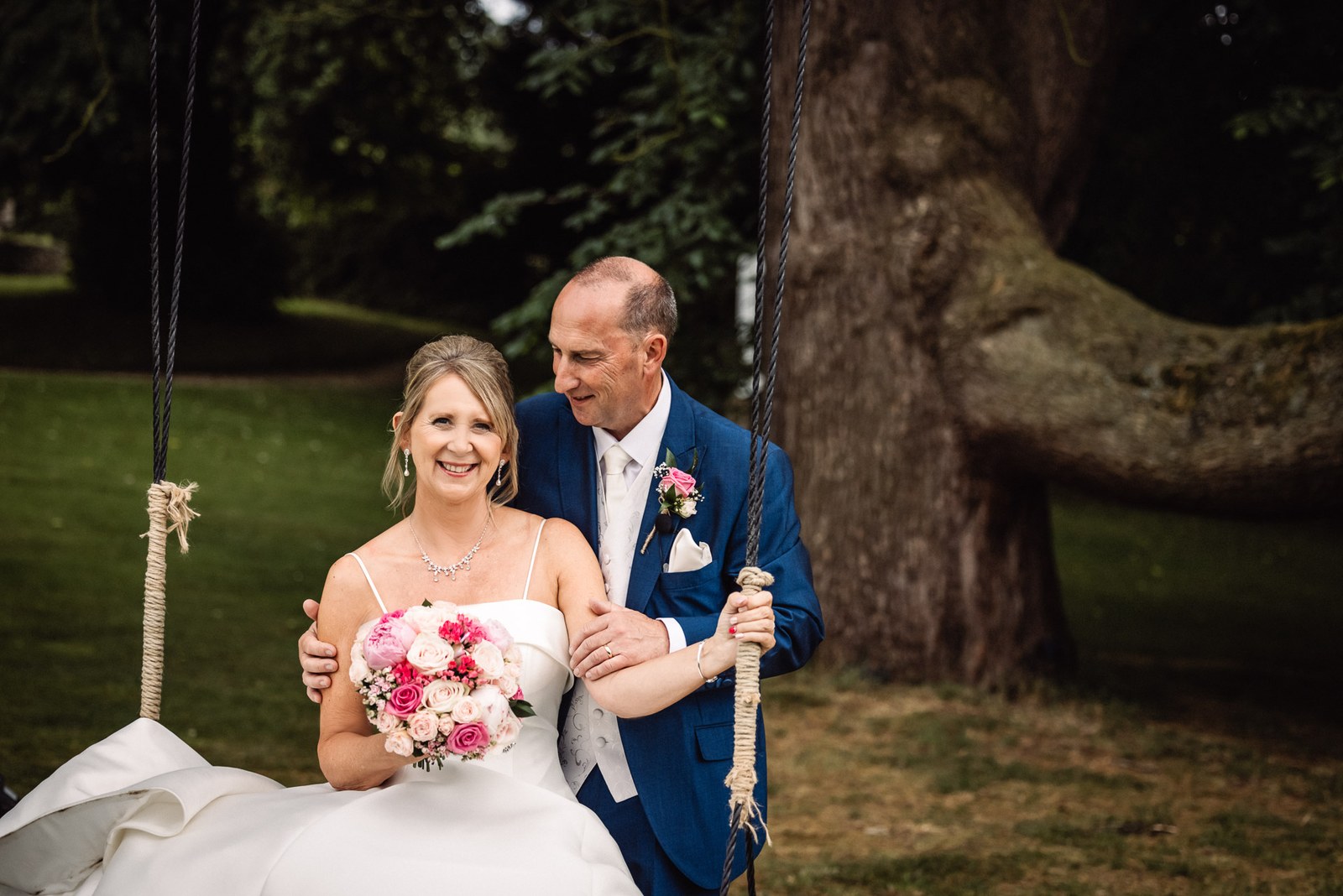 Bride and groom together on the rope swing in the grounds of Glenfall House