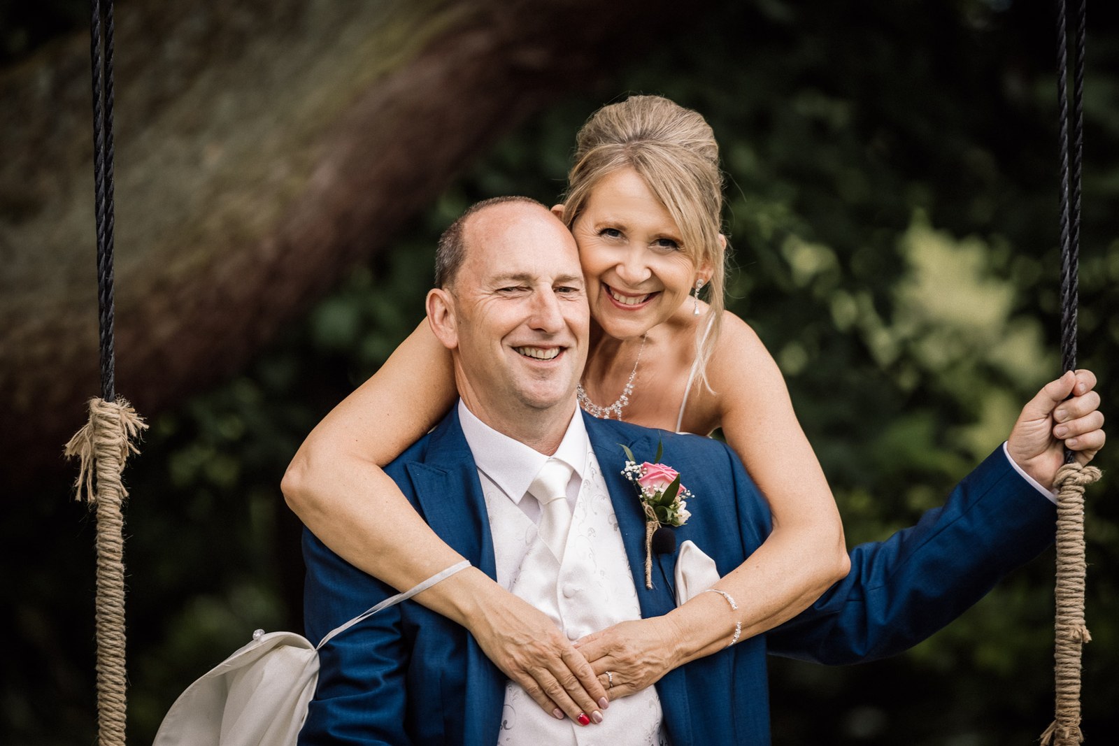 The bride wrapping her arms around the groom on the garden swing
