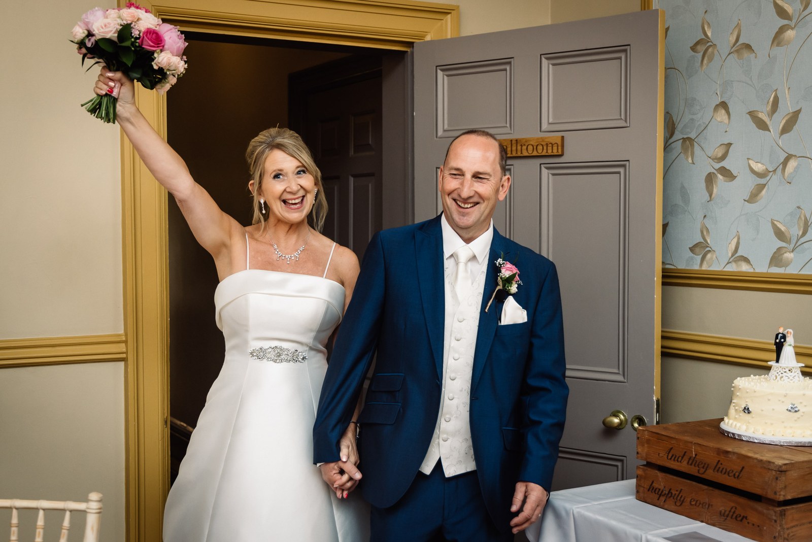 The newlyweds entering the ballroom, the bride raising her bouquet