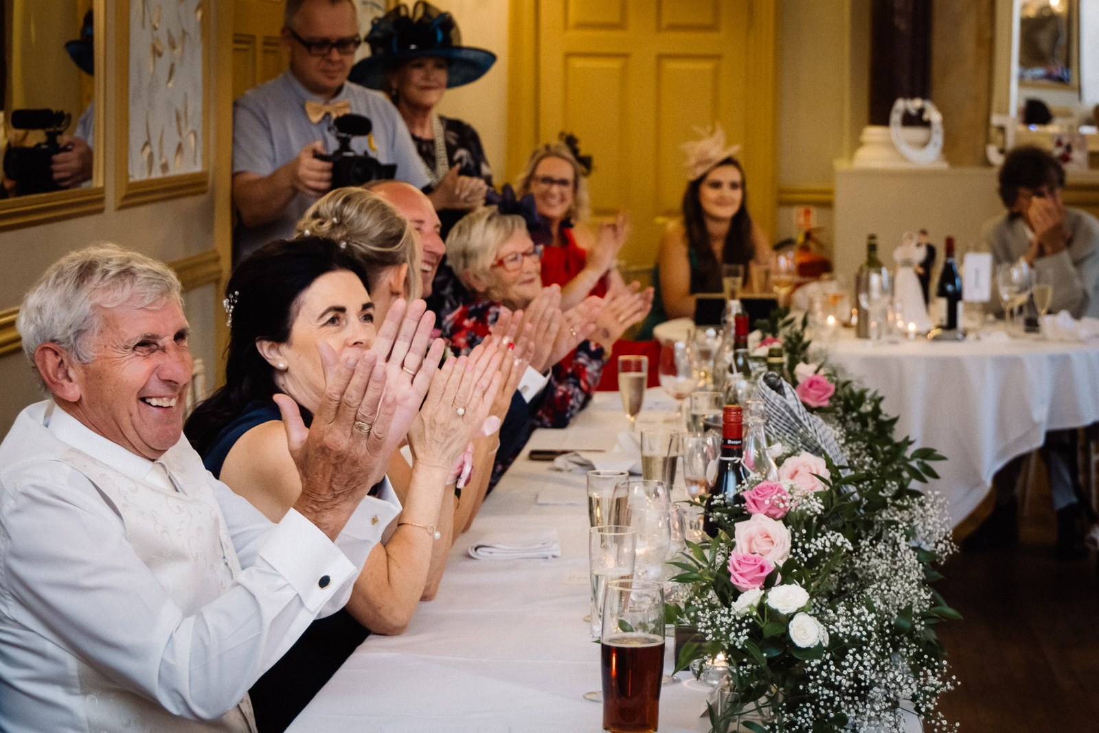 Guests applauding at the flower-lined top table during the speeches