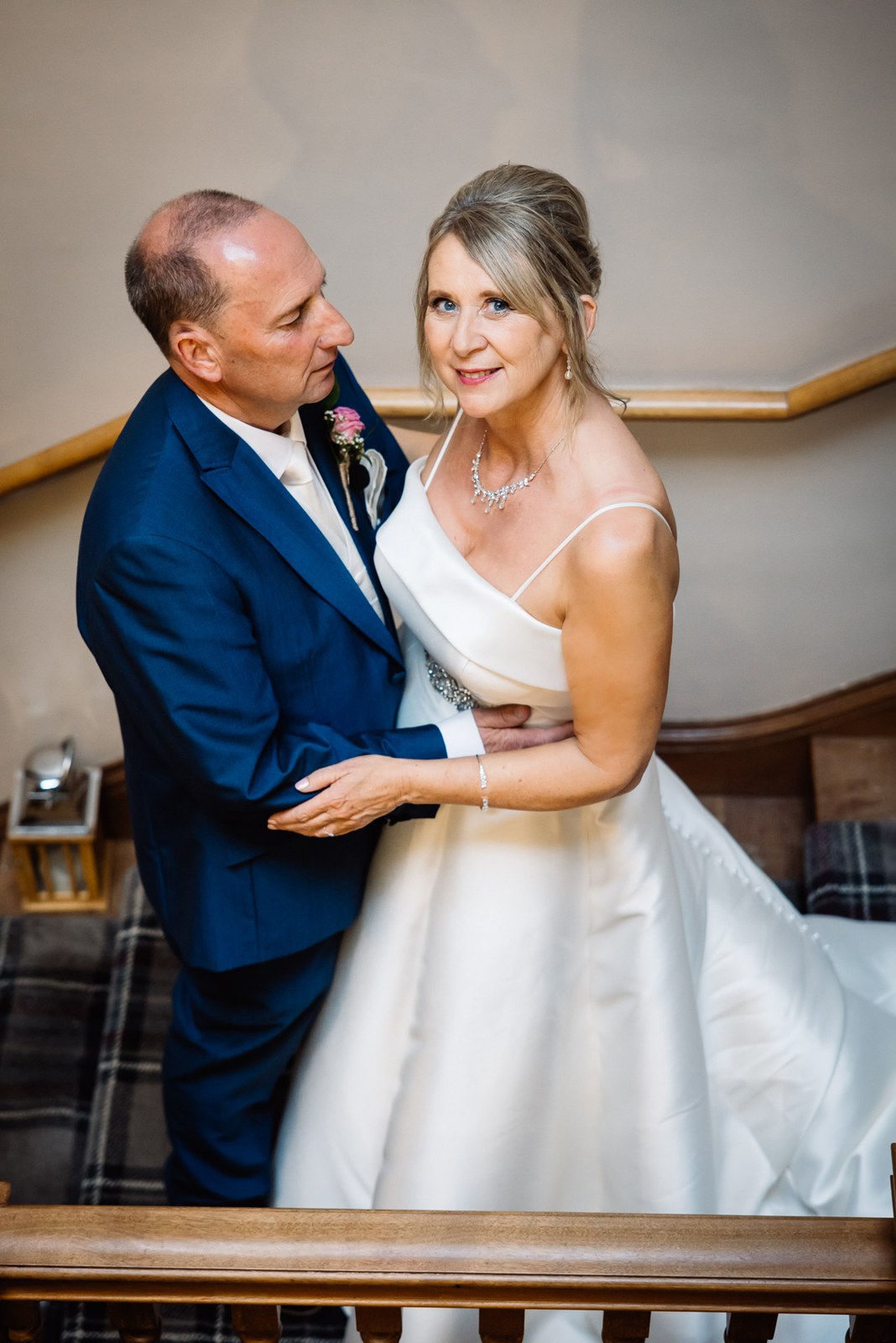 Bride and groom in a quiet embrace on the staircase landing