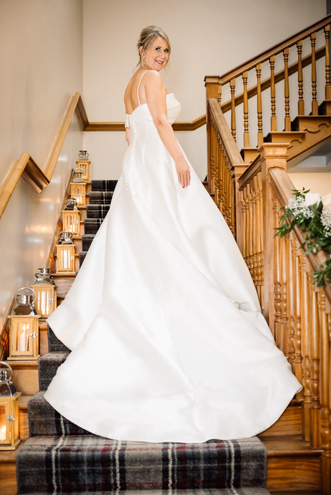 Bride on the staircase with her gown's train spread across the lantern-lined steps